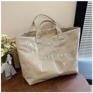 Dettaglio della borsa tote in PVC trasparente con scritta TOTE BAG e bottone a pressione