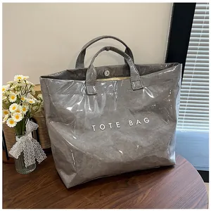 Dettaglio borsa tote grigia impermeabile con texture increspata e finitura lucida su legno