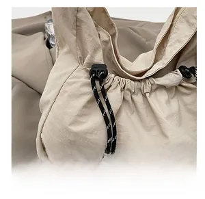 Détail du cordon de serrage en nylon et boucle réglable sur le sac bandoulière beige