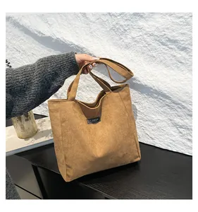 Détail du sac cabas en daim marron avec une étiquette de mode noire cousue dessus