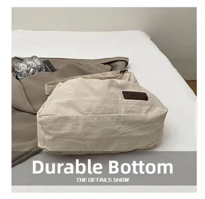 Détail du fond large et résistant de ce sac à bandoulière en nylon de couleur crème