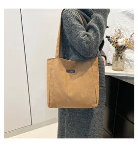 Détail d'un sac cabas en daim marron avec étiquette Fashion Instinct et pull en maille gris