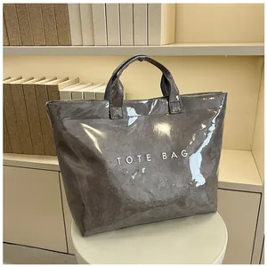 Dettaglio ravvicinato di una borsa tote grigio scuro lucida con scritte bianche grandi