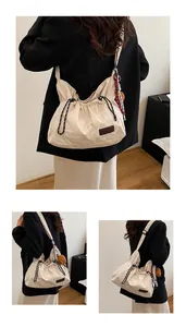 Détail du sac bandoulière blanc cassé avec cordon de serrage et breloques de mode