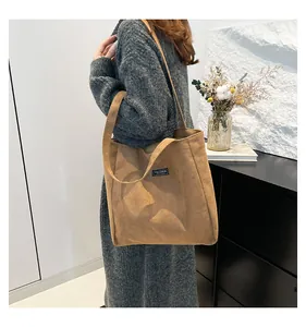 Détail d'un grand sac cabas en daim marron avec étiquette mode sur un mannequin en pull