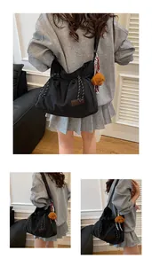 Détail du sac bandoulière en nylon noir avec plis coulissants et charm d'ours marron