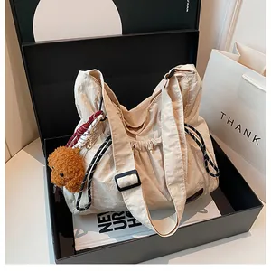 Détail du sac beige en nylon à cordon avec texture plissée et charmant ours en peluche