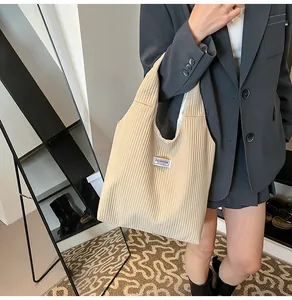 Detail of beige corduroy tote bag with fashion label shown by a model for commuting