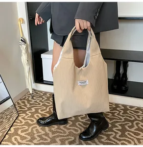 Detail of beige pleated corduroy tote bag showing vertical ribbed texture and fashion label