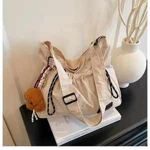 Détail du sac à bandoulière à cordon avec pendentif ours et étiquette en cuir mode