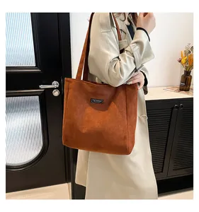Détail du sac cabas marron en velours côtelé avec étiquette Fashion sur manteau beige