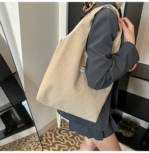 Close-up of the beige corduroy tote bag showing textured fabric and fashion side label
