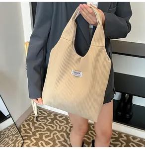 Detail of khaki corduroy tote bag showing ribbed texture and fashion logo patch