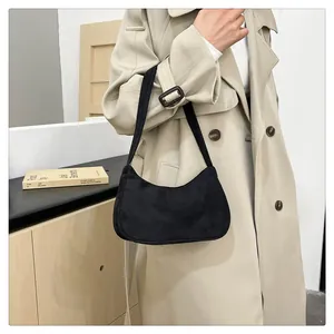 Detailopname van de zwarte suède baguette tas met matte textuur en hobo-stijl look