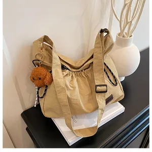 Détail du sac bandoulière en nylon avec cordon de serrage et pendentif chien en peluche