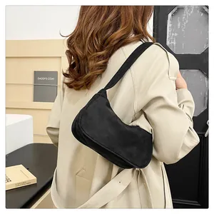 Detailweergave van een zwarte suède baguette-tas op een model voor maatperspectief