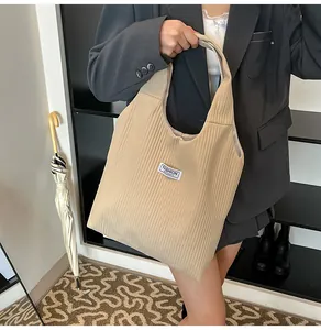 Detail of beige corduroy tote bag showing ribbed texture and minimalist brand label