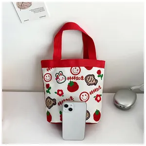 Detail der Cartoon-Canvas-Tasche mit roten Griffen und festlichen Glücksmustern