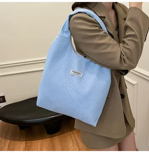 Close-up of light blue corduroy tote bag featuring vertical texture and logo label