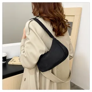 Zwarte suède baguette tas gecombineerd met een beige jas voor een modieuze look