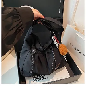 Détail du sac à bandoulière en nylon noir avec cordon de serrage et breloque peluche