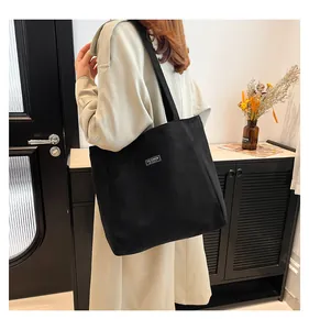 Détail du sac cabas noir en daim avec étiquette de mode et texture nervurée douce