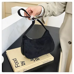 Minimalistische zwarte suède hobo-tas getoond in een natuurlijke lifestyle-omgeving