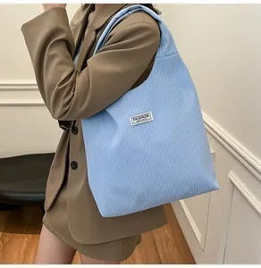 Detail of light blue corduroy tote bag featuring a white Fashion Instinct label on the front
