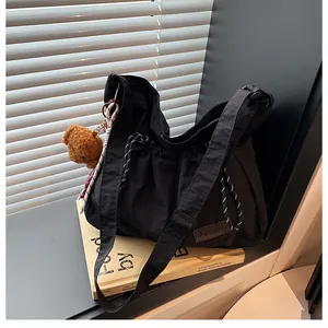Détail d'un sac bandoulière en nylon avec cordon de serrage et pendentif ours brun