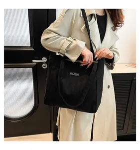 Détail de la texture côtelée et de l'étiquette sur le grand sac cabas noir en velours côtelé