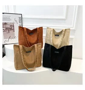 Détail de quatre sacs cabas en daim en marron, noir, beige et havane avec étiquette