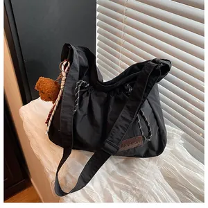 Gros plan d'un sac en nylon noir avec étiquette en cuir et pendentif ours en peluche