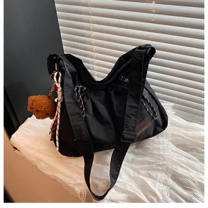 Détail du sac bandoulière en nylon noir avec cordon et breloque ours mignonne