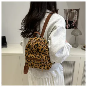 Mini-Rucksack aus Cord mit Leopardenmuster, getragen von einem Model im Innenraum