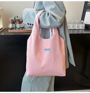 Detailed close-up of pink pleated corduroy tote bag with white fashion logo label