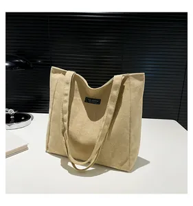 Détail du sac cabas en daim beige montrant la texture velours et l'étiquette de marque