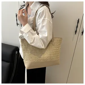 Detail of straw woven tote bag featuring beige PU leather base and sturdy shoulder straps