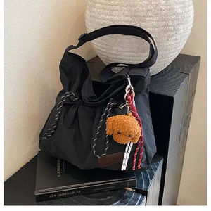 Détail du sac bandoulière en nylon noir avec étiquette fashion et breloque caniche