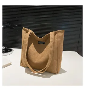 Détail du sac cabas en daim caramel avec étiquette noire et larges bretelles