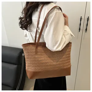 Detail of straw tote bag featuring herringbone weave texture and brown leather straps