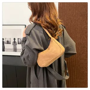Bruine hobo tas van imitatiesuède getoond op model met een grijze lange jas