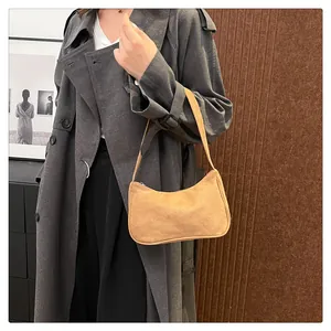 Detail van vintage suède baguette tas in gemberbruin met bijpassende schouderriem
