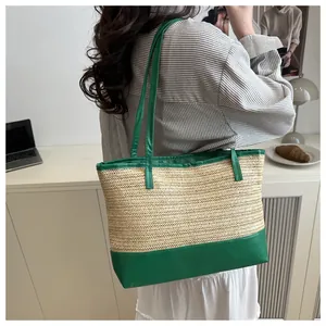 Detail of straw tote bag with green leather handles and base worn by a model in casual setting