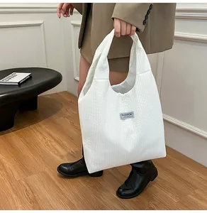 Detail of white corduroy tote bag with Fashion Instinct label and ribbed texture