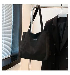 Détail du sac cabas en daim noir avec étiquette Fashion Instinct suspendu dans un bureau