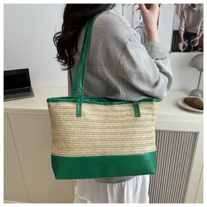 Detail of woven straw tote bag with green faux leather handles in office setting