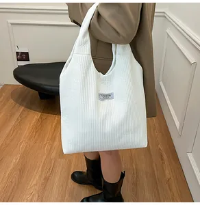 Detail of white quilted corduroy tote bag showing the Fashion Instinct letter patch