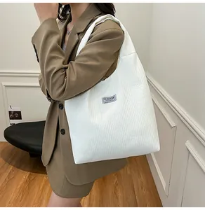 Detail of white corduroy tote bag featuring a Fashion Instinct side label and wide strap
