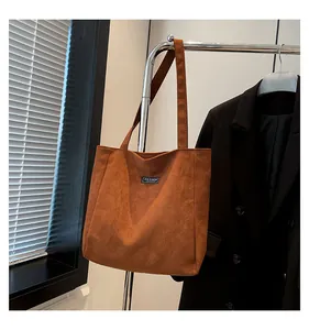 Gros plan d'un sac cabas en daim caramel avec étiquette tendance sur cintre en métal