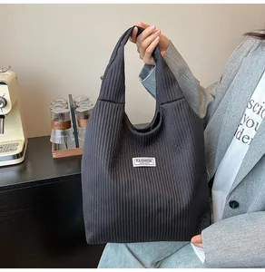 Detail of black corduroy tote bag with vertical texture and Fashion Instinct logo label